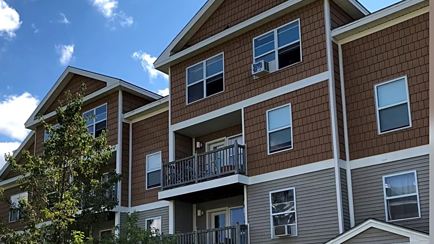 An apartment complex with wooden decks and a bright blue sky.